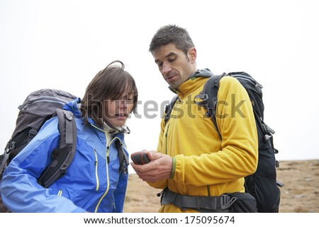Close up of backpacker holding in his hand GPS navigator, Global Positioning System device. Mountain white background.