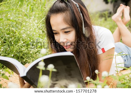 Woman relaxing in garden with book and music