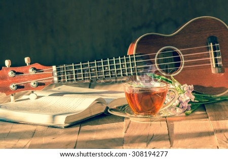 Cup of tea on table with ukulele and book.