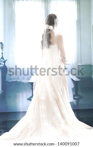 full-length beautiful smiling girl in a white wedding dress back posing in studio
