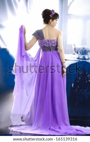 Full body young and beautiful bride in purple dress back in studio