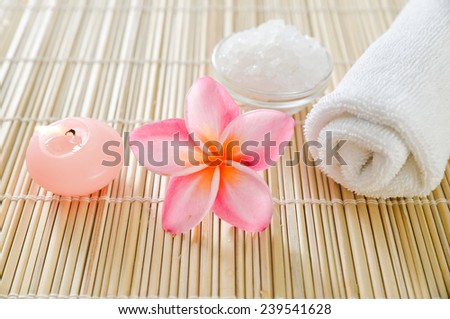 Pink frangipani with salt in bowl ,towel,candle on bamboo and bamboo mat texture