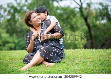 Happy Asian family ,mother with her son playing on green grass at park
