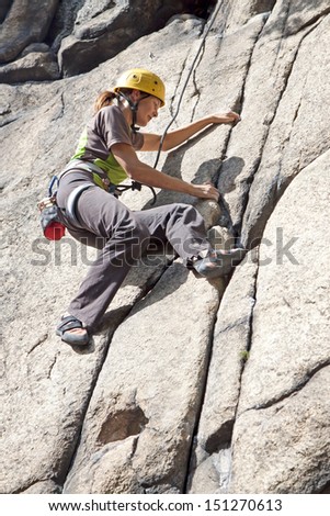 Young woman climbing on a wall, rock climbing in mountains with natural background.