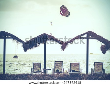Retro vintage filtered picture of beach and paragliders at sunset.