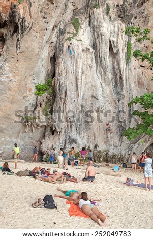 Railay, Thailand - December 31, 2014: Tourist watching rock climbers climbing the wall on Railay beach, one of the most popular rock climbing locations in Asia.