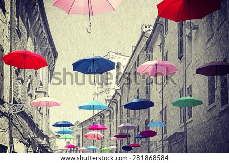 Retro vintage filtered colorful umbrellas hanging above street of Ferrara, black and white background.