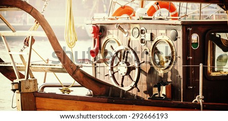 Retro vintage filtered photo of old sailing boat bridge with wooden steering wheel.