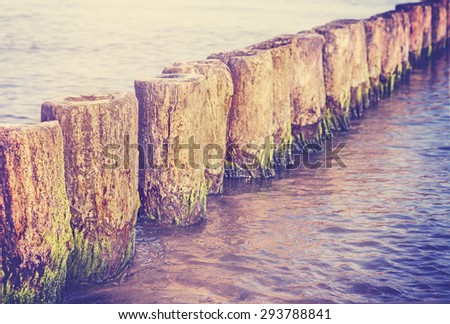 Retro filtered blurred abstract background made of wooden posts in water, shallow depth of field, space for text.