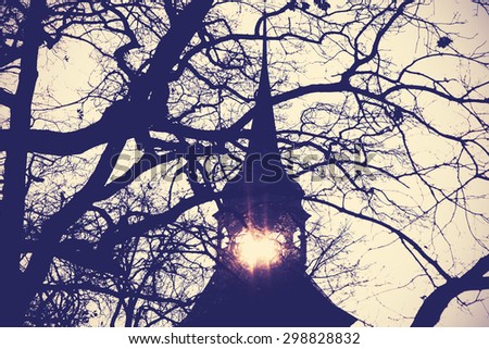 Vintage instagram filtered photo of mysterious or scary church bell tower silhouette at sunset.