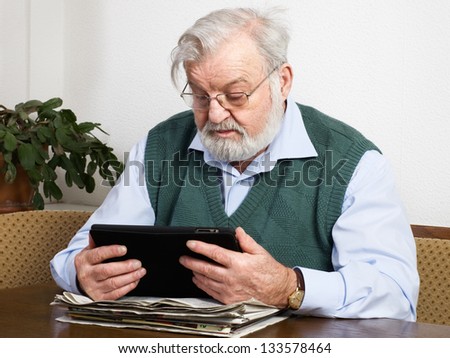 Senior man reading newspaper on digital tablet