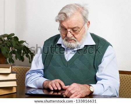 Senior man reading book on digital tablet