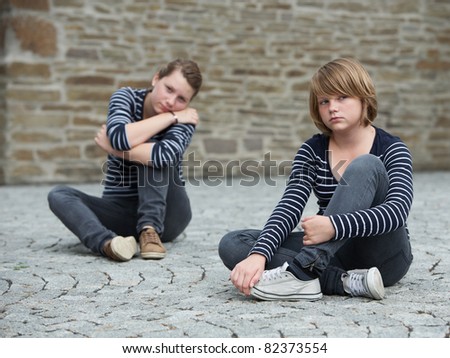Teenage girls sitting on grounds, turned away from one another