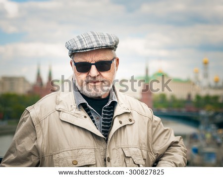 Portrait of old man in sunglasses and cap. Tourist in front of the Kremlin, Moscow. Travel destination.
