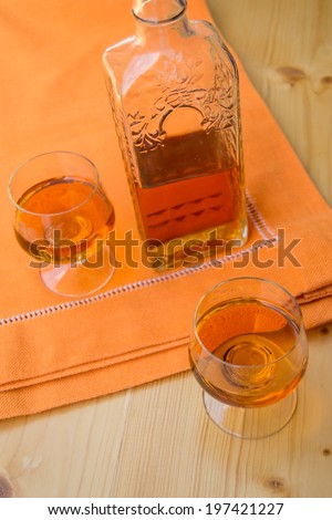 Glass and bottle of hard liquor like scotch, bourbon, whiskey or brandy on wooden background