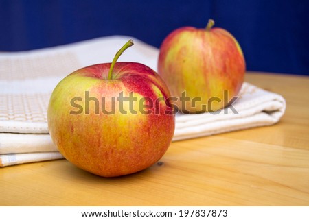 two apples on wood table with white texture and blue background