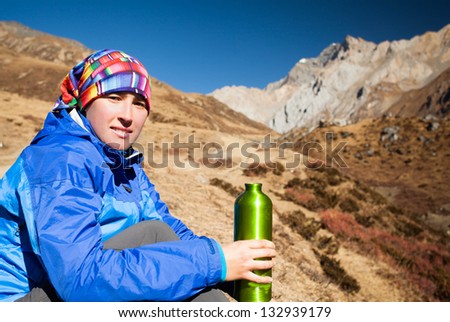 happy girl drinking water among the snow, high mountains of Himalayas