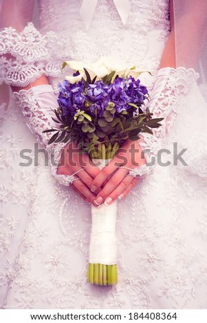 Bride is holding a bouquet of blue hydrangeas with white calla lilies