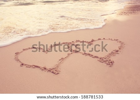 heart outline on the wet brilliance beach sand against wave