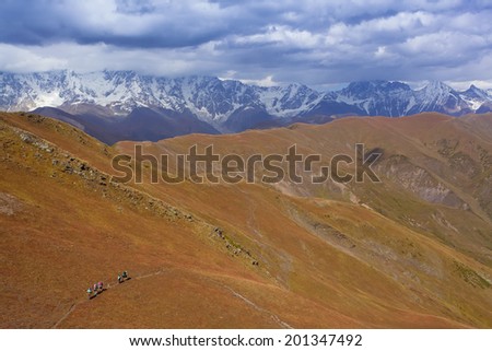 group of friends in hiking in high mountains.  snow-capped peaks, glaciers and  Fantastic sky background with blue clouds. Beautiful world
