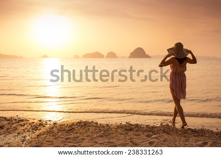 Happy Woman in a hat and short dress enjoys in Sea Sunset. In the background hilly karst mountains to the sea,  vintage color