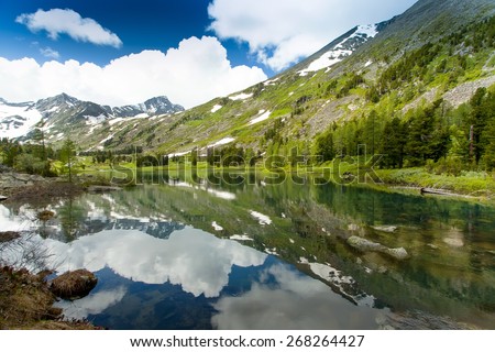 Beautiful landscape of a mountain lake Altai, Siberia. High mountains with snow-capped mountains, blue sky with beautiful clouds.