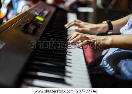 hands of musician playing keyboard in concert with shallow depth of field