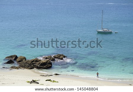 Man on seashore. Clean beach, fresh sea water and boat in a sunny day. Summer and spring time.