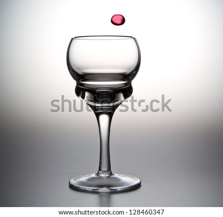 Single drop of pink liquid falling into stemmed cordial glass/A Dop of Pink