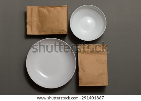Set of paper bags, bowl, and plate isolated on grey background