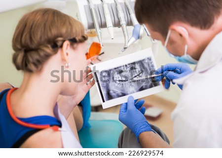 Healthcare, medicine. Young woman with dentist in a dental surgery.
