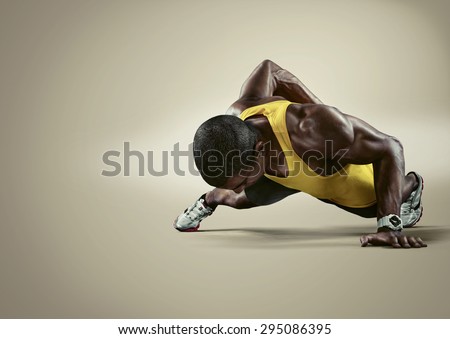Sport. Young athletic man doing push-ups. Muscular and strong guy exercising. Isolated