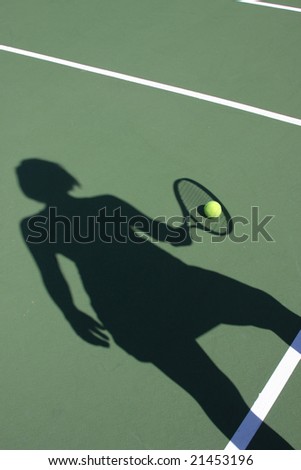Woman\'s shadow holding racket with tennis ball on court
