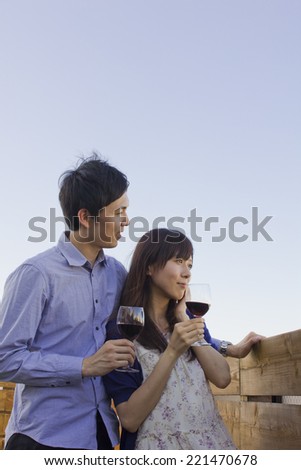 Young couple looking ahead with glasses of red wine