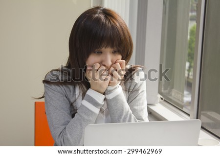 Young woman shocked in front of computer