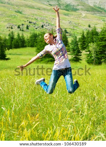 Active sporty woman jumping outdoors, beautiful happy girl play on wheat field, healthy young lady having fun outside, pretty female enjoying nature,cheerful teen wearing blue jeans, freedom concept