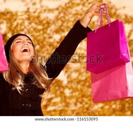 Photo of attractive woman expressing joy of her new purchase, happy good looking girl with pink shopping bags walking in autumn park, money spending and  antistress concept, autumnal sale