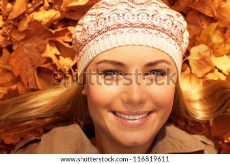 Photo of cute young lady laying down on the ground in autumn park