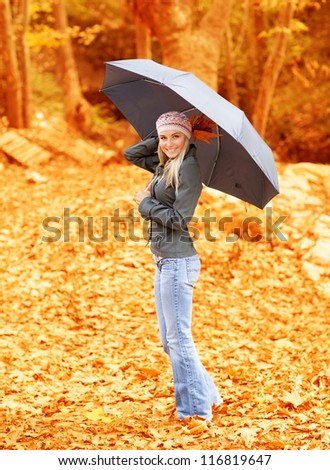 Photo of lovely woman walk under umbrella in rainy day in autumnal park