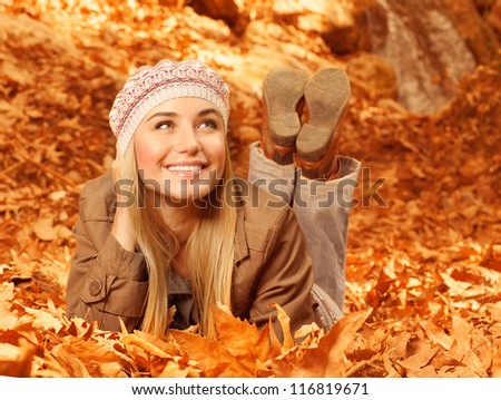 Picture of pretty cheerful woman lay down on the ground covered dry autumnal foliage