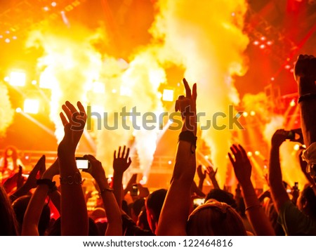 Photo of rock concert, music festival, New Year eve celebration, party in nightclub, dance floor, disco club, many people standing with raised hands up and clapping, happiness and night life concept