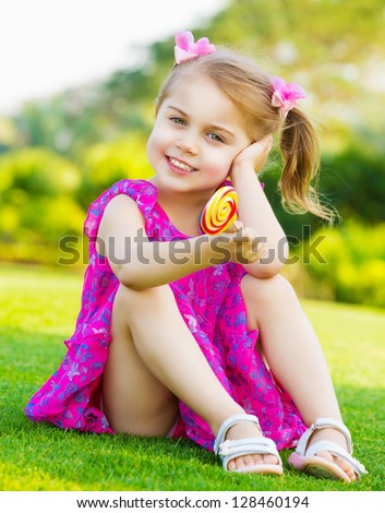 Photo Of Cute Little Girl Sitting On Green Grass On Backyard And ...