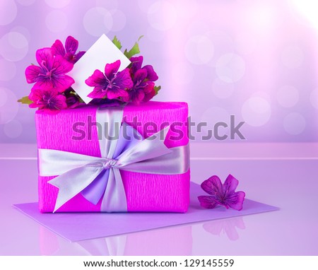 Picture of pink gift box with purple silk ribbon, beautiful violet wild flowers bouquet, white blank greeting card, beautiful romantic still life, blur background, happy mothers day, reflection