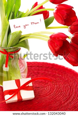 Fresh red tulip flowers bouquet in glass vase, spring holiday greeting card, little white gift box, happy mothers day