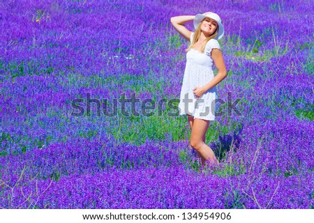 Pretty girl tanning in lavender glade, enjoying bright sun light and purple flowers landscape, having fun outdoors in summer time