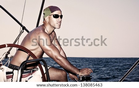 Handsome strong man working on sail boat, sailor enjoys crew duty, luxury lifestyle, yachting sport, traveling the oceans, summer vacation concept