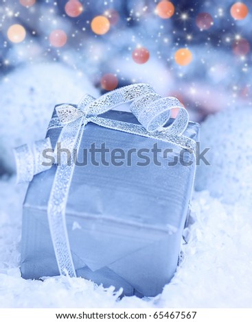 Winter holiday background with blue present gift box, silver ribbon ornament & Christmas snow decoration