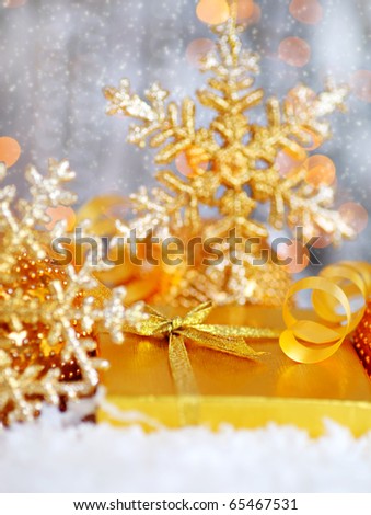 Winter holiday background with golden present gift box, Christmas tree snowflake ornament  & defocus lights decoration