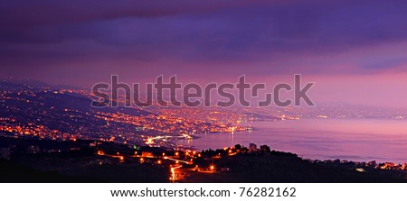 Panoramic mountains city at night with purple sky & sea