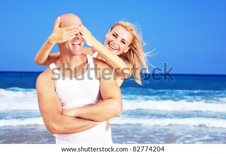 Happy couple having fun on the beach, young new family spends honeymoon at tropical resort, playing game, handsome man & beautiful woman in love, vacation & travel concept